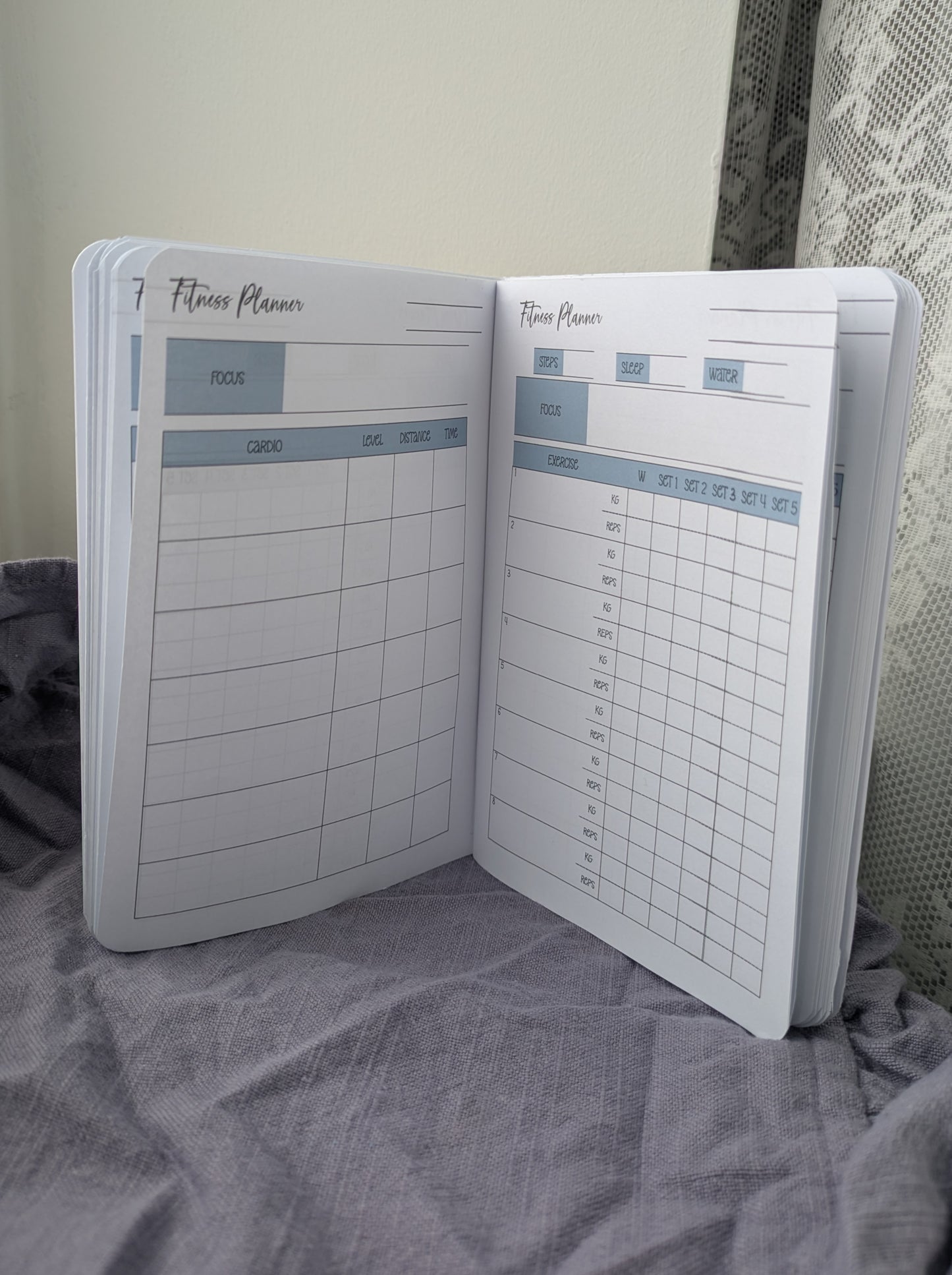 Fitness planner notebook open on a textured surface with a neutral background